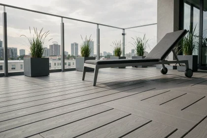 Terrasse moderne avec revêtement composite en lames grises posées en chevrons sur un balcon urbain avec balustrades en verre